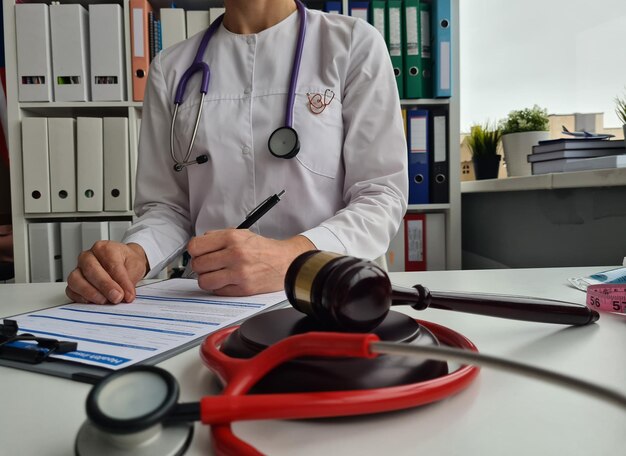 Photo wooden judge gavel on table of medical clinic and doctor doing paperwork