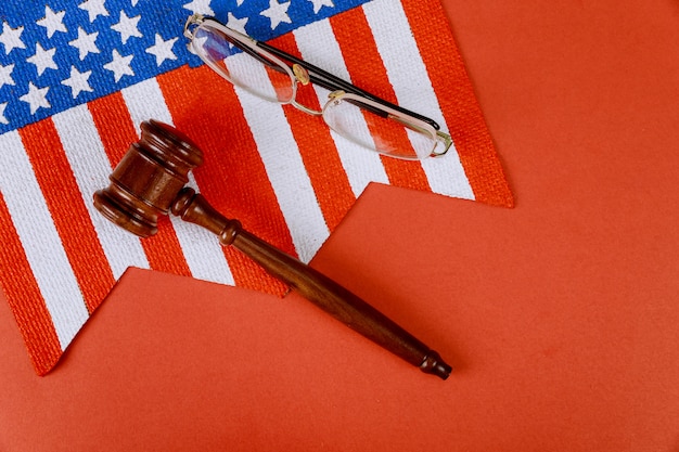 Martelletto dei giudici in legno su di occhiali da lettura e bandiera usa sul tavolo del giudice di legge