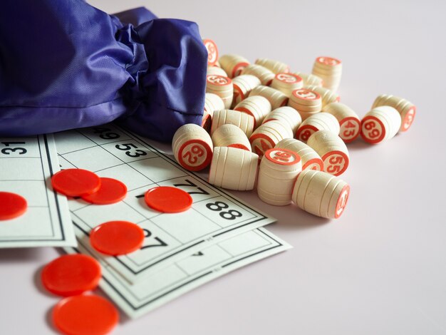 Wooden kegs of lotto, playing cards for playing lotto with a bag on a pale lilac