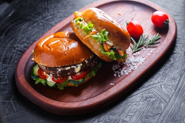 Wooden kitchen board, cutting tray, sesame and meat patty burger, cherry tomatoes, dark and moody