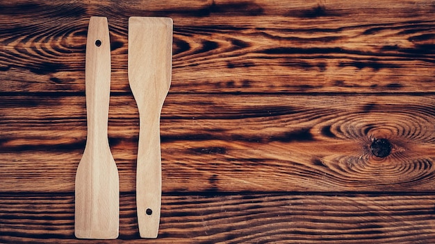 Wooden kitchen spatulas on brown table background