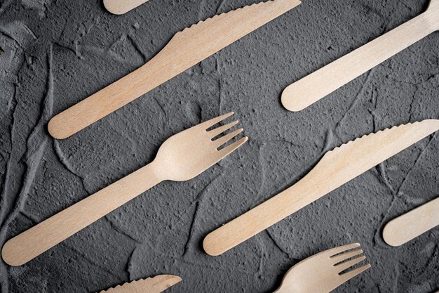 Wooden knife and fork on the black background Eco friendly zerowaste concept Top view with space for text Copy space