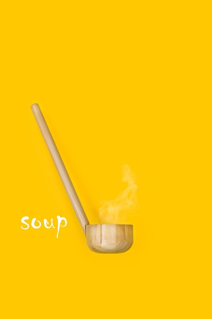 A wooden ladle with steam on a yellow background