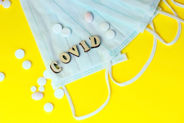 Wooden letters are lined with the word covid pills with a medical mask