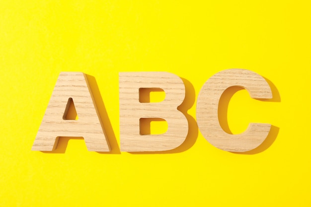 Wooden letters of English alphabet on yellow background