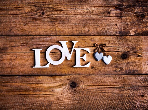Wooden letters forming word LOVE and hearts on wooden surface