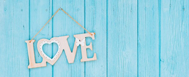 Wooden letters forming word love sign on a rope on a wooden blue background rustic styl