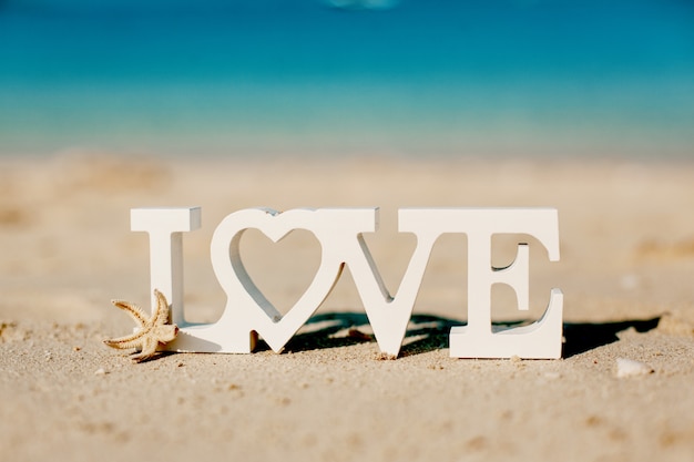 Wooden letters love on a sandy beach overlooking the blue sea