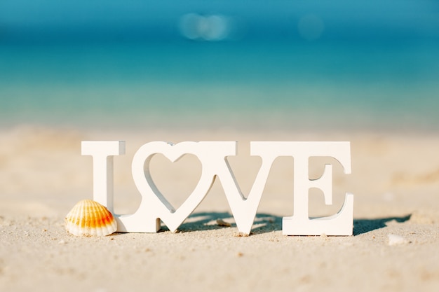 Wooden letters love on a sandy beach overlooking the blue sea