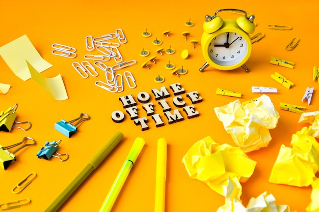 Wooden letters text home office time with office supplies in front yellow background copy space