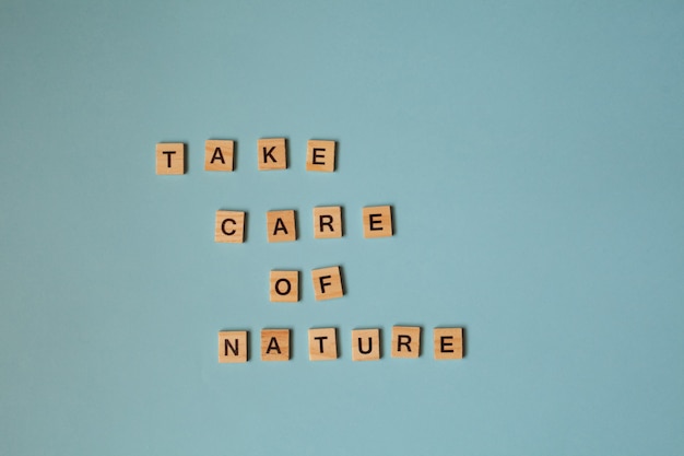 wooden letters with the inscription take care of nature light wooden letters on a blue background