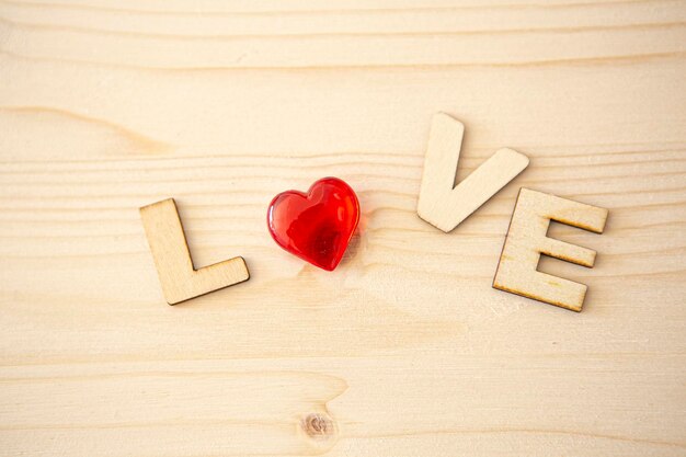 Wooden letters with the word love written on white background and red heart