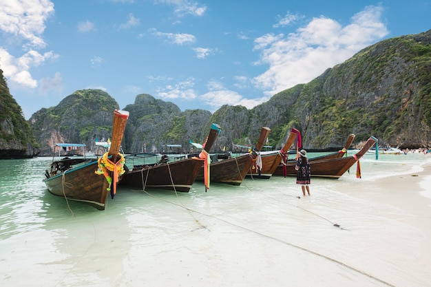 タイのマヤ湾で熱帯の海を旅する女性と一緒に停泊する木製のロングテールボート