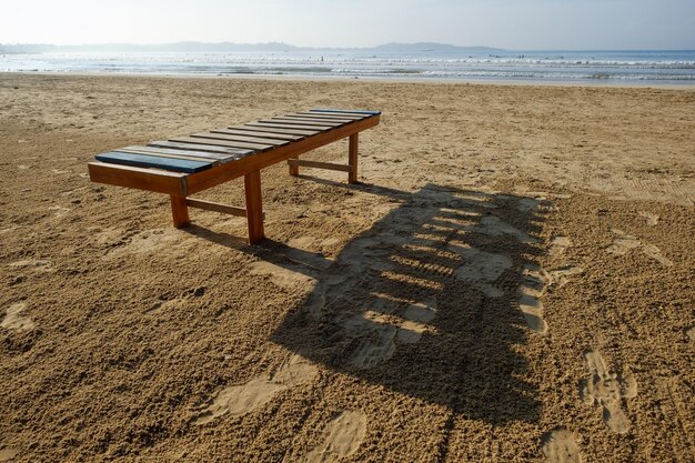 Wooden lounger on sandy beach near ocean