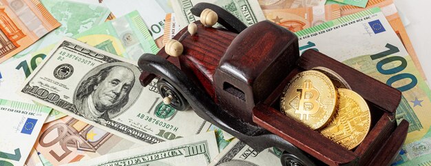 Wooden machine with bitcoins on euro and dollars texture background panorama