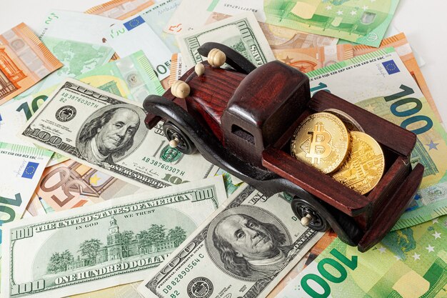 Photo wooden machine with bitcoins on euro and dollars texture background