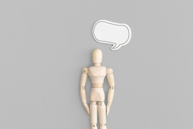 Wooden man with speech bubble on a gray background