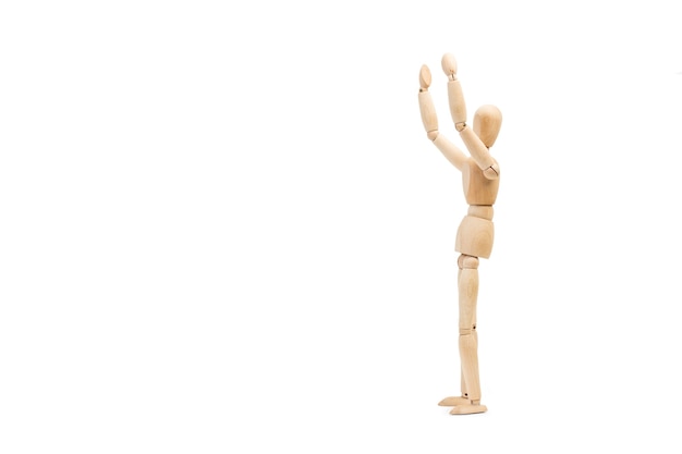 A wooden manequin toy with arms raised on white