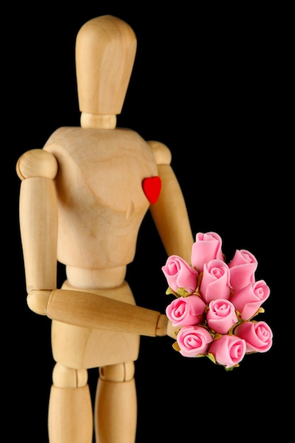 灰色の背景に花束を保持している木製のマネキン