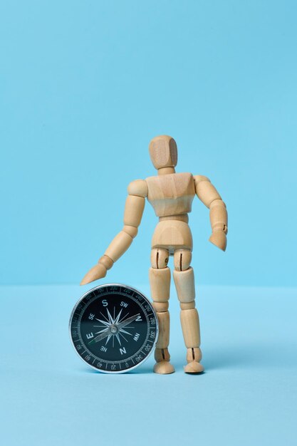 Wooden mannequin and round compass on a blue background