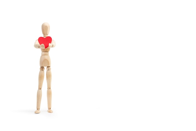 A wooden mannequin toy holding a red paper heart on white