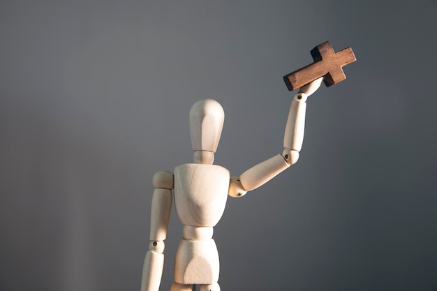 Wooden mannequin with cross on his hand