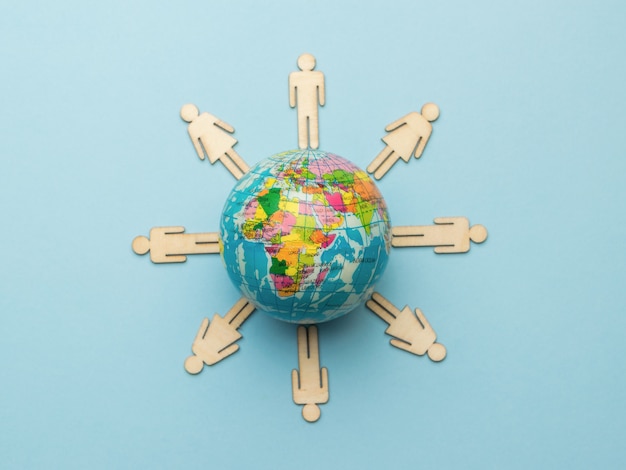 Wooden men around a model of the globe on a blue background.