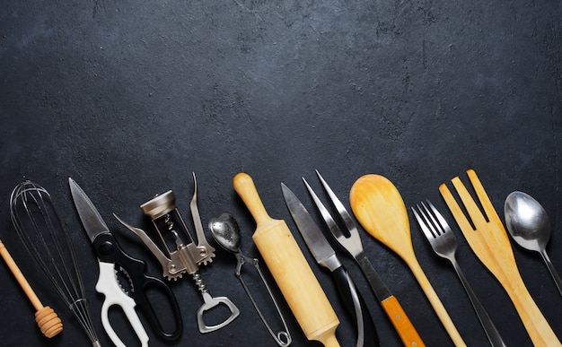 Photo wooden and metal kitchen utensils. tools for cooking. dark background. flat lay. copy space