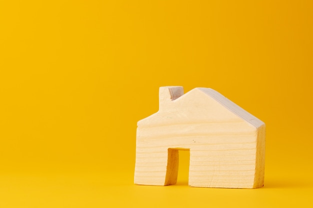 Wooden mini house model on yellow background close up