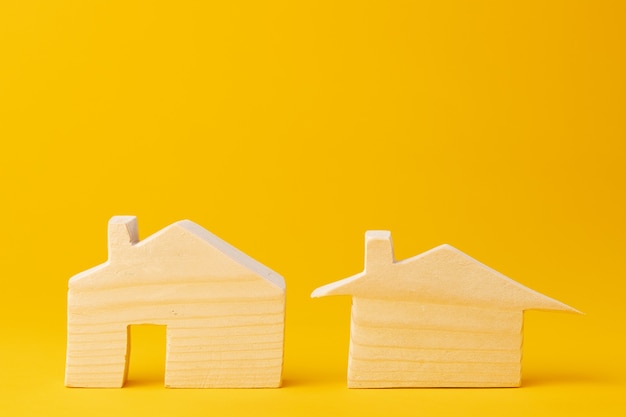 Wooden mini house model on yellow background close up