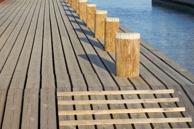 Photo wooden mooring bollards with shadows on the mole.