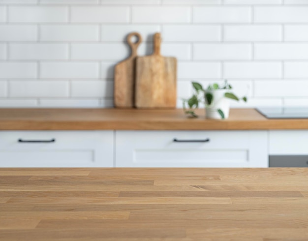 Wooden oak countertop with free space for mounting a product or layout against the background of a blurred white kitchen with plant