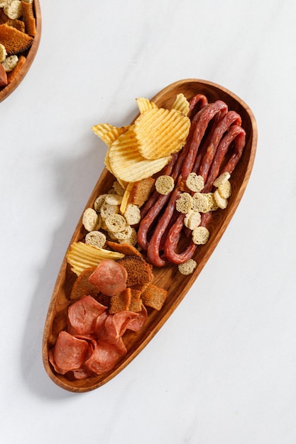 Wooden oak oval dish plate with beer snacks potatoes chips meat chips sausages kabanos crackers