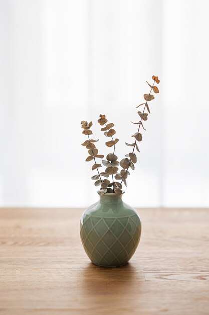 Wooden oak table top with a green vase with eucalyptus branches