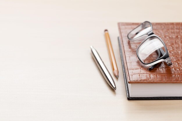 Wooden office desk with supplies. Notepad, pen and glasses. With space for your text