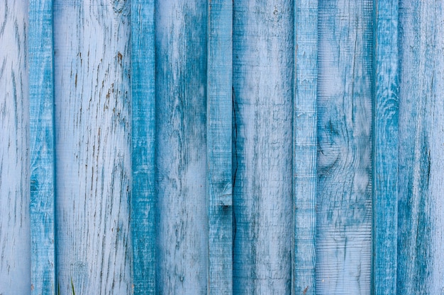 Wooden old blue fence with peeling and cracked paint