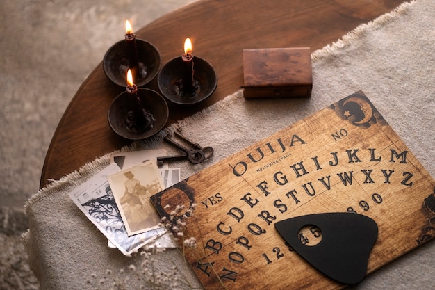 Wooden ouija board and lit candles high angle