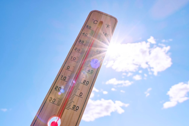 Wooden outdoor thermometer background scorching summer sun and blue sky