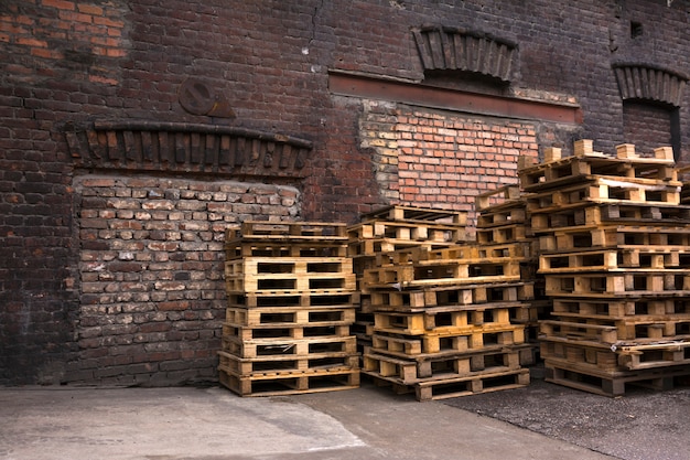 木製パレットは古い倉庫の庭に積み上げられています。