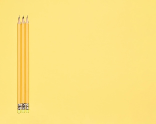 Wooden pastel yellow pencils with erasers on yellow background Monochromatic Copy space Top view