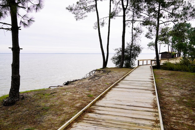 Wooden pathway in Maubuisson coast beach aside Carcans lake water in southwest france