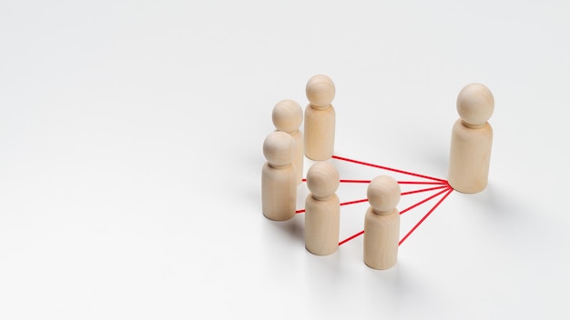 Photo wooden peg dolls are connected together with red lines on white background teamwork leadership