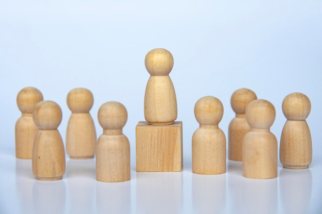 Wooden people figure on top of wooden cube leading the rest of\
the wooden figure