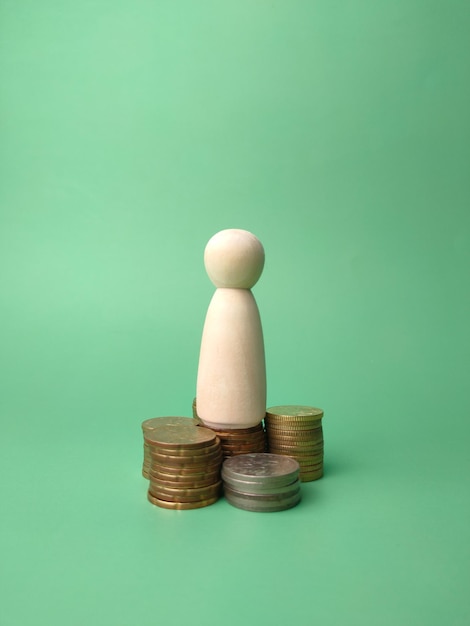 Wooden people figures and coins on a green background