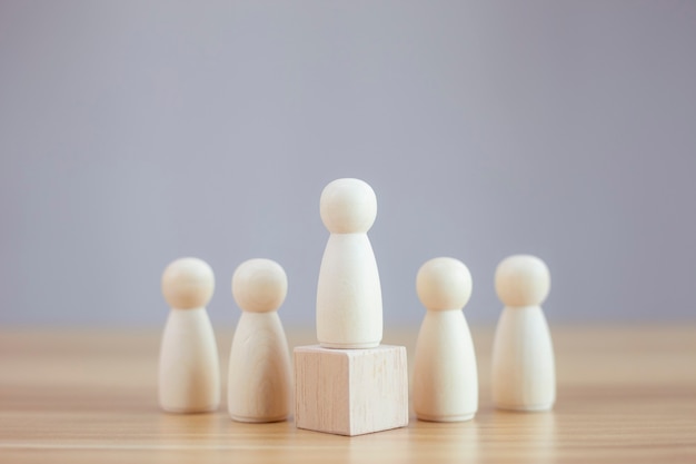 Wooden person model among people on black background Leadership concept