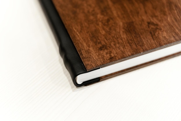 Fotolibro in legno su sfondo chiaro scudo metallico album fotografico elegante e modernoun libro marrone con copertina in legno giace su un panno di lino creazione di un'idea concetto innovazione o pianificazione
