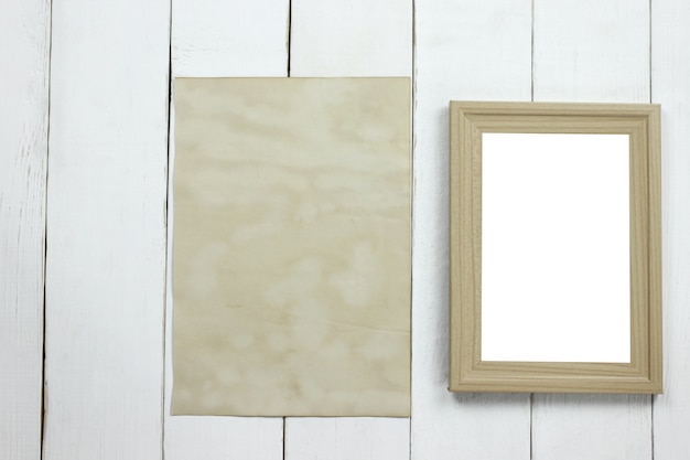 Portafoto in legno e vecchia carta d'epoca vuota sul pavimento di legno bianco.