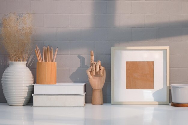 Foto cornice in legno libri portamatite e tazza di caffè sul tavolo bianco