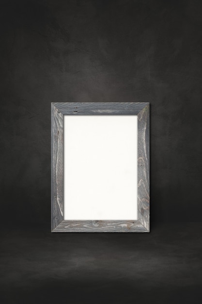 Wooden picture frame leaning on a black wall. Presentation mockup template