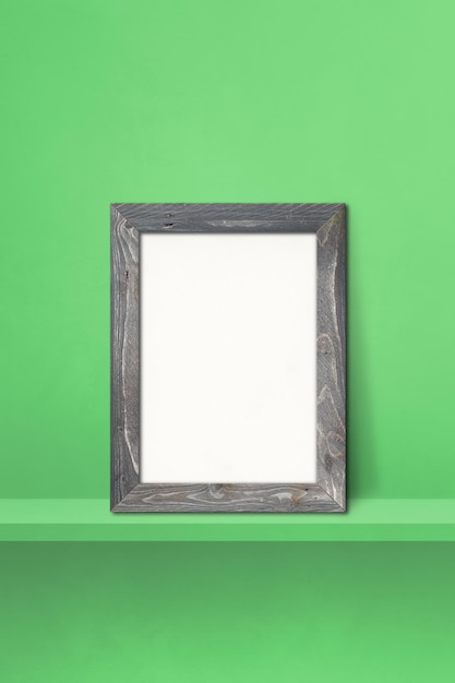 Wooden picture frame leaning on a green shelf. 3d illustration. Blank mockup template. Vertical background